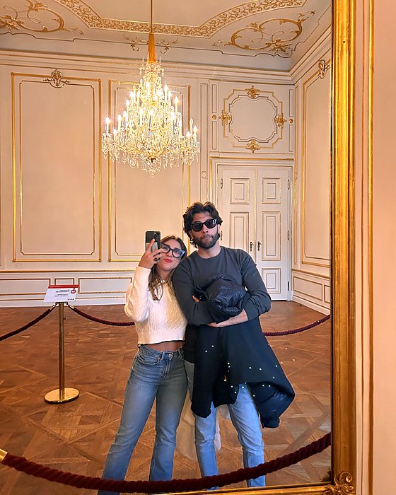 Un selfie allo specchio di coppia in una sala del palazzo con un grande lampadario