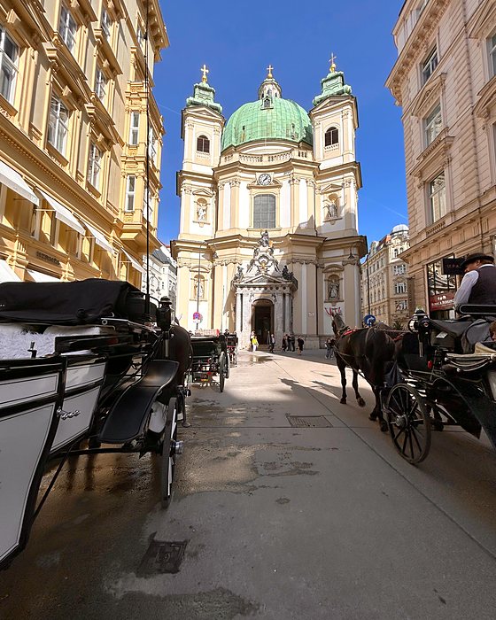 La Peterskirche con la cupola verde e delle carrozze a cavalli in primo piano